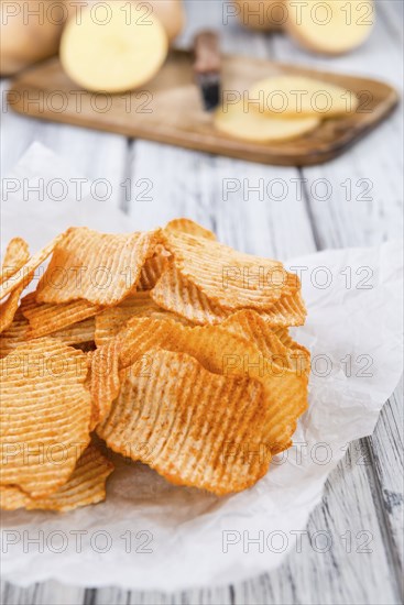 Bowl with rippled Potato Chips (selective focus) on wooden background