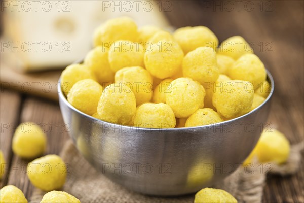 Cheese Balls on an old wooden table as detailed close-up shot (selective focus)