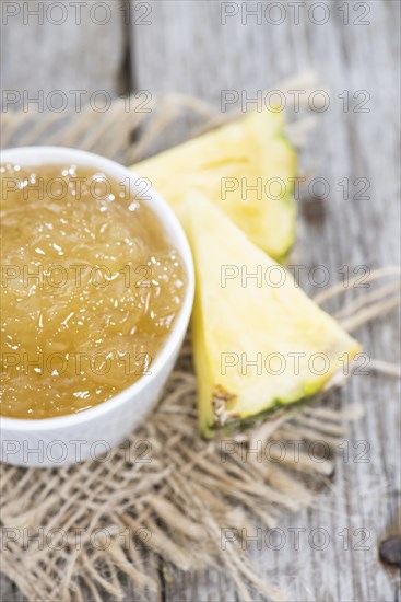 Small bowl with Pineapple Jam (close-up shot on wood)