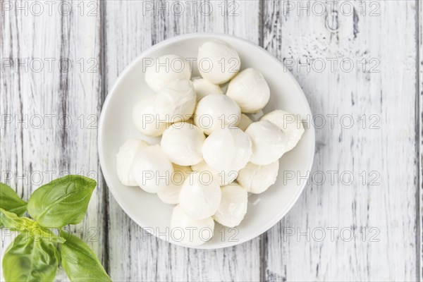 Small Mozzarella balls (on wooden background, selective focus) as close-up shot