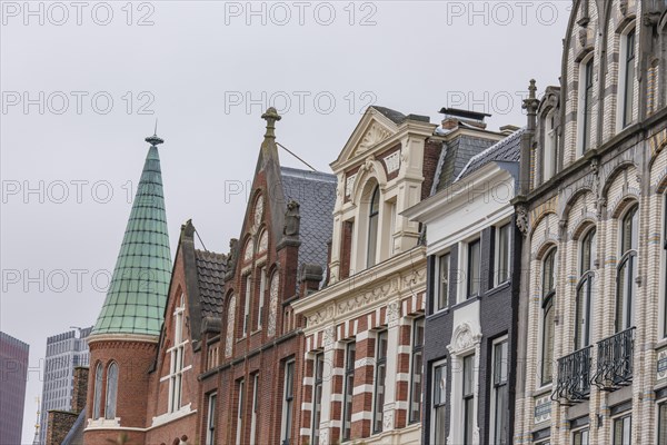 A row of historic townhouses with different facades and roof shapes under a cloudy sky, The Hague,