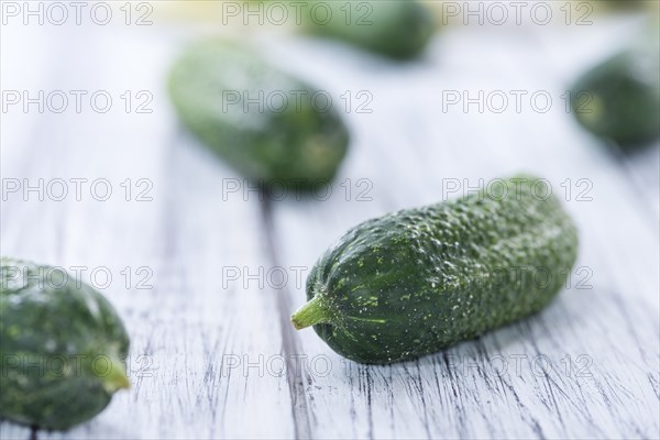 Small green Gherkins (detailed close-up shot) on wooden background