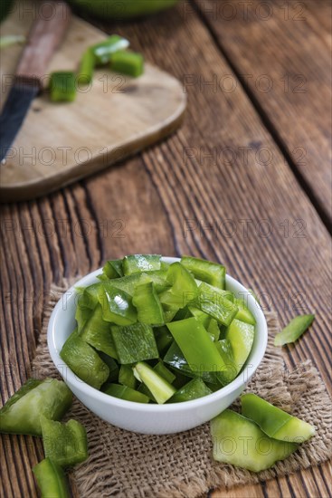 Portion of green Peppers (sliced, selective focus) on wooden background