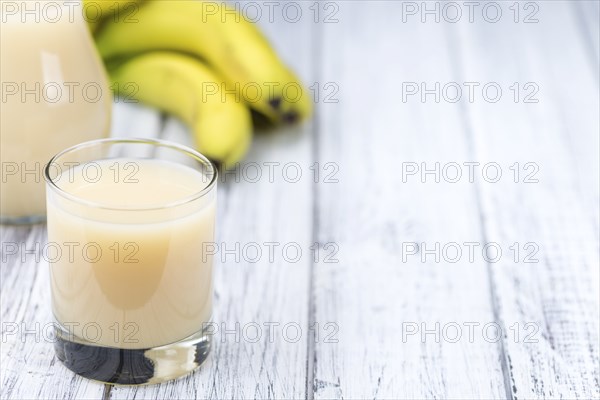 Banana juice (selective focus) on an old wooden table (detailed close-up shot)