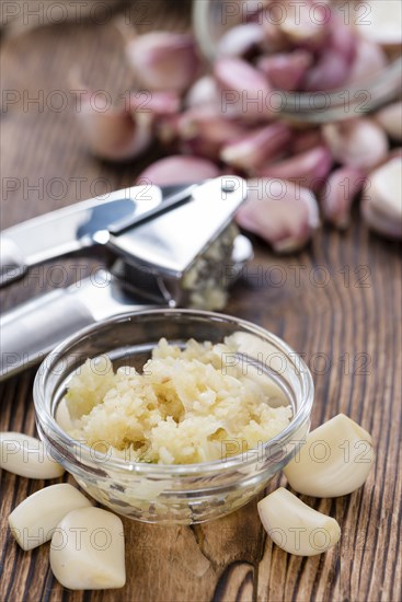 Crushed Garlic (close-up shot) on rustic wooden background