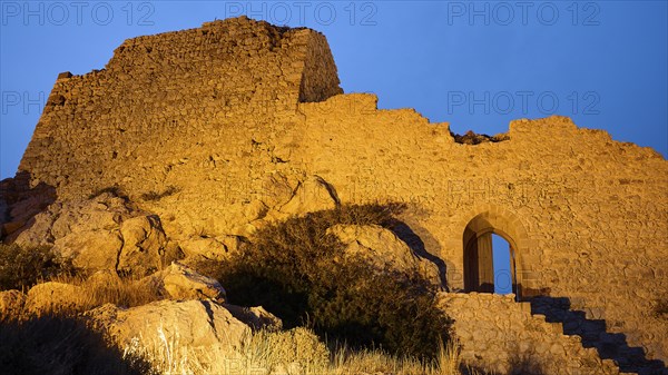 Night shot, close-up of an illuminated old castle ruin with stone steps and an archway at night,