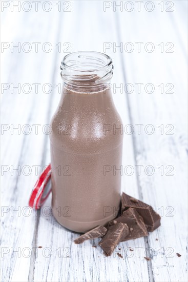 Chocolate Milk in a small bottle (on bright wooden background)