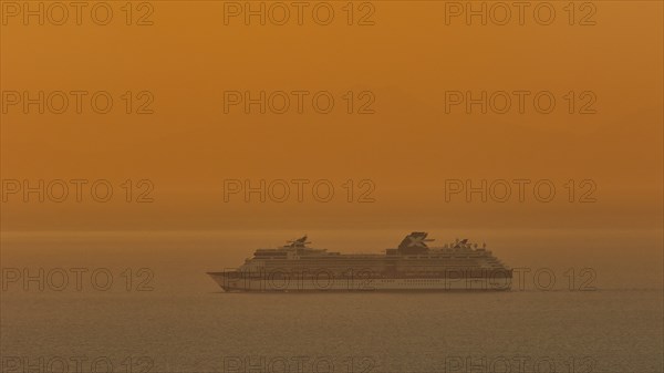 Large cruise ship sails through the calm, orange-coloured sea at sunset, Kritinia Castle, St John's