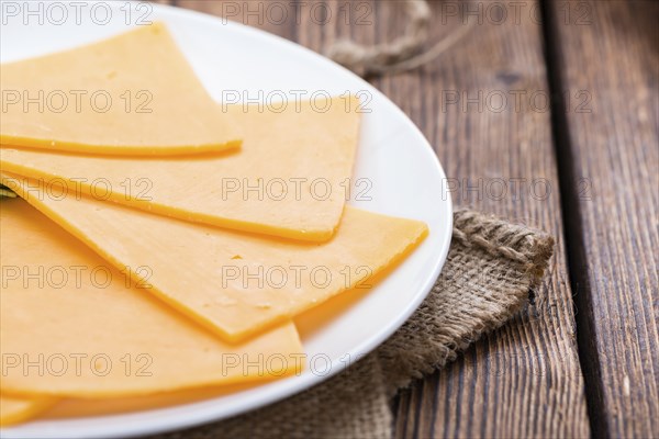 Portion of Cheddar Slices on wooden background (close-up shot)