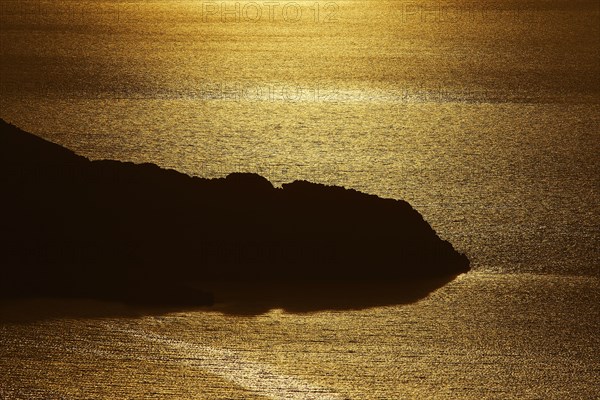 Coastal silhouette at sunset, the golden light reflected in the calm water, Kritinia Castle, St