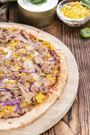 Fresh made Tuna Pizza (close-up shot) on rustic wooden background