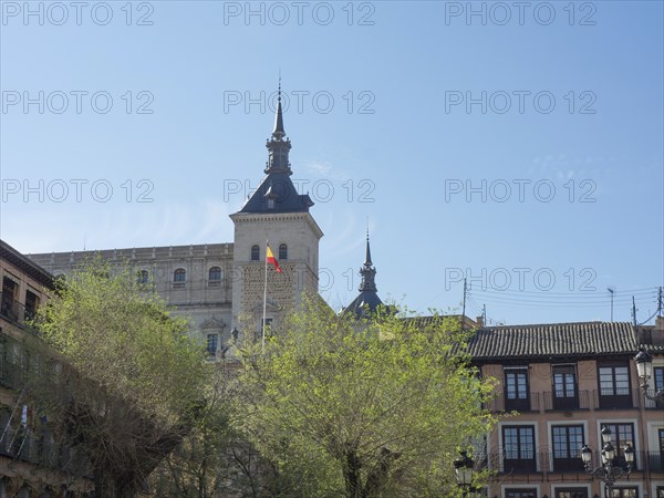 Historic tower rises above green trees, radiating a calm and spring-like atmosphere under a clear