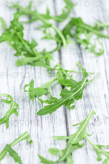 Fresh Arugula (selective focus) as detailed close-up shot on vintage background