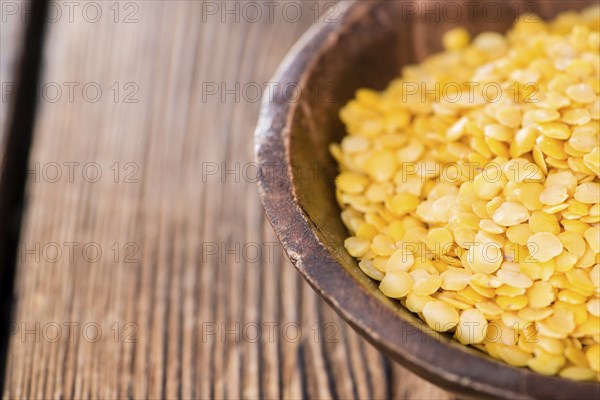 Yellow Lentils (detailed close-up shot) on wooden background