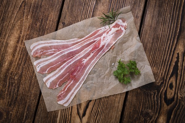 Portion of raw Bacon (close-up shot) on wooden background