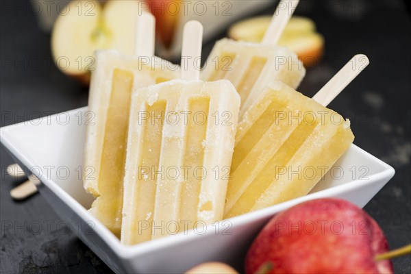 Portion of homemade Apple Popsicles (selective focus, close-up shot) on a vintage background
