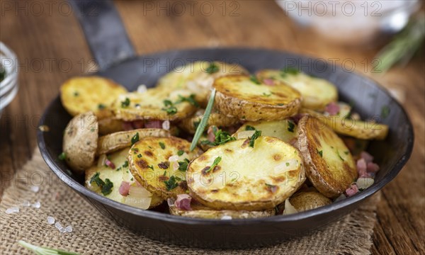 Fried Potatoes with Onions ond ham on a wooden table (selective focus)