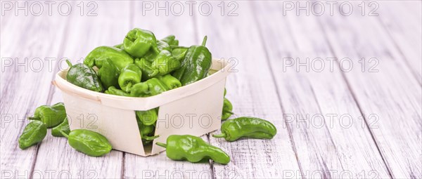 Raw Pimientos on rustic wooden background as close-up shot