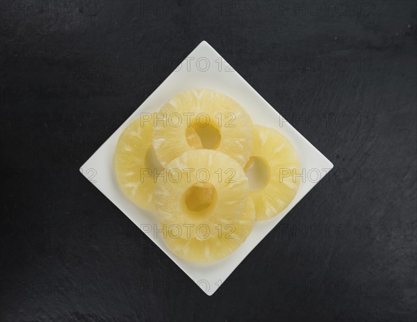 Some fresh Preserved Pineapple Rings on a vintage slate slab, selective focus, close-up shot