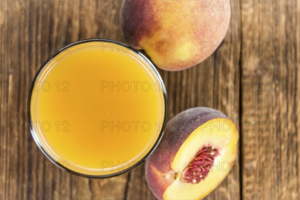 Portion of Peach juice (fresh made) on an old wooden table (close-up shot)