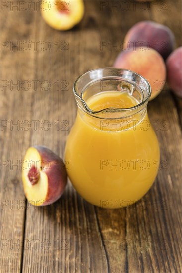 Portion of Peach juice (fresh made) on an old wooden table (close-up shot)