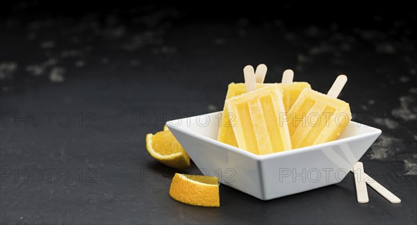 Some homemade orange popsicles on a vintage background (selective focus, close-up shot)