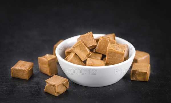 Portion of Caramel candy as detailed close up shot on a slate slab (selective focus)