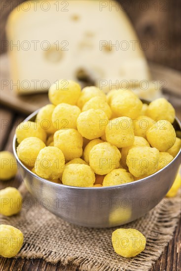 Cheese Balls (fried) as high detailed close-up shot on a vintage wooden table (selective focus)