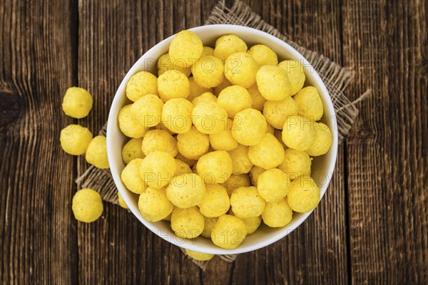 Cheese Balls on rustic wooden background (close-up shot)