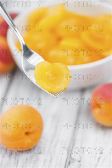 Canned Apricots on an old wooden table as detailed close-up shot (selective focus)