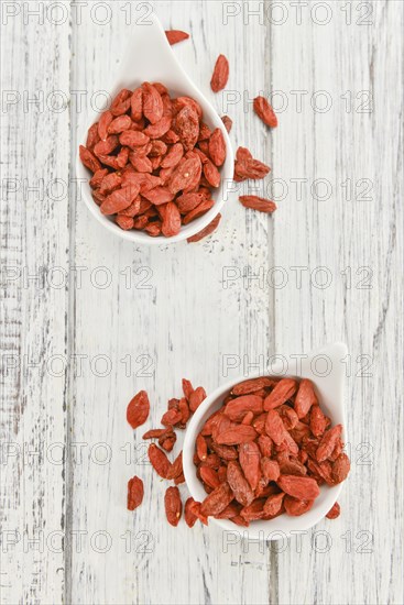 Dried Goji Berries as high detailed close-up shot on a vintage wooden table (selective focus)