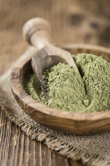Portion of Stevia leaf powder (detailed close-up shot) on rustic wooden background