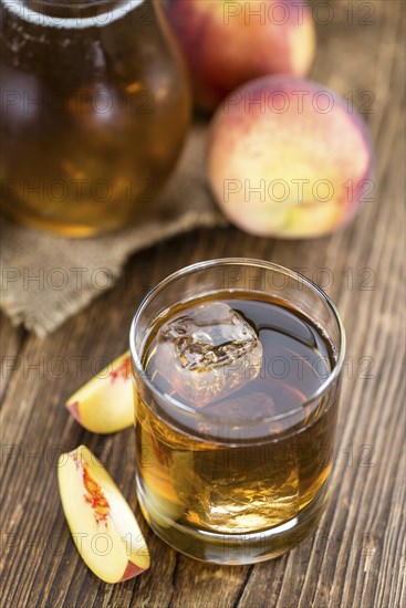 Ice Tea (Peach) on an old wooden table (selective focus, close-up shot)