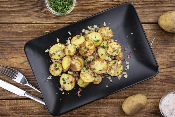 Fried Potatoes with Onions ond ham on a wooden table (selective focus)