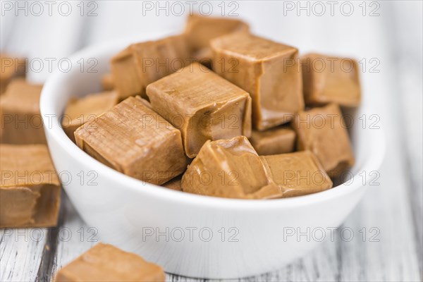 Caramel pieces as high detailed close-up shot on a vintage wooden table (selective focus)