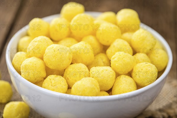 Cheese Balls on an old wooden table as detailed close-up shot (selective focus)