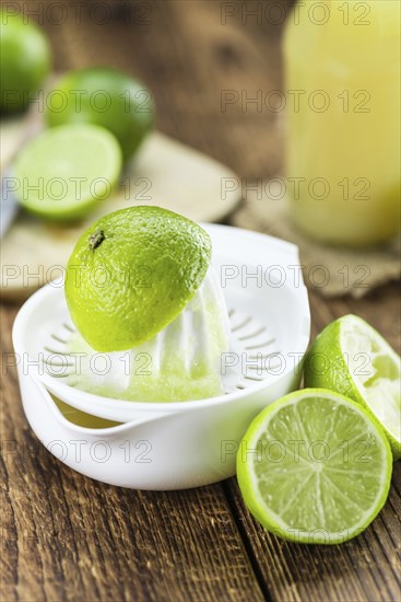 Fresh Lime Juice as high detailed close-up shot on a vintage wooden table (selective focus)