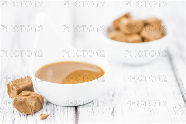 Caramel Sauce on an old wooden table as detailed close-up shot (selective focus)