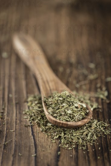 Old wooden table with dried Stevia leaves (close-up shot, selective focus)