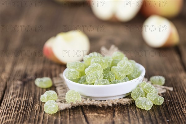 Wooden table with sour gummy candy (apple taste) as detailed close-up shot