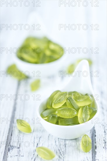 Heap of gummy candy with lime taste on wooden background (selective focus, close-up shot)