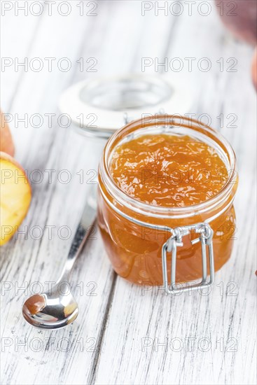Wooden table with Peach Jam (selective focus, close-up shot)