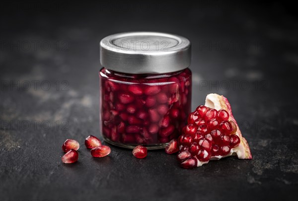 Healthy preserved Pomegranate seeds on a vintage slate slab (close-up shot, selective focus)