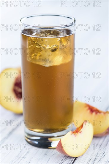 Ice Tea (Peach) on an old wooden table (selective focus, close-up shot)
