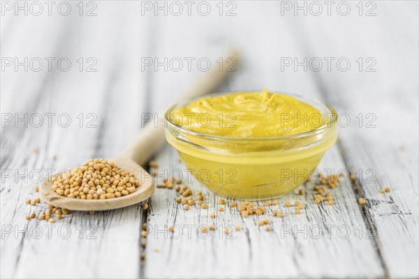 Fresh made Mustard on a vintage background (close-up shot)