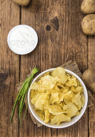 Fresh made Potato Chips with Sour Cream taste on a vintage background (close-up shot)