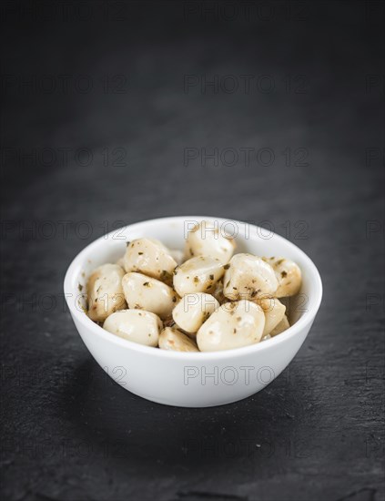 Portion of Garlic (preserved) on a rustic slate slab (selective focus, close-up shot)