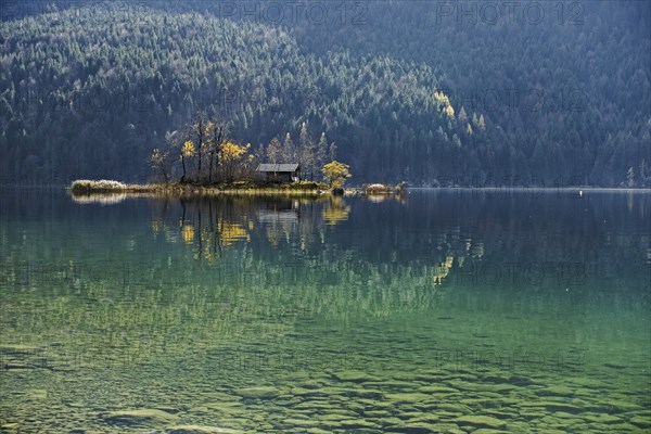 Island with wooden hut in autumn in Lake Eibsee lake in the Bavarian Alps