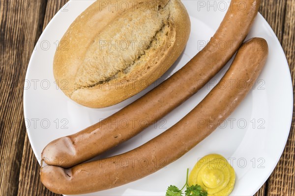 Sausages (Frankfurter) on rustic wooden background (close-up shot)