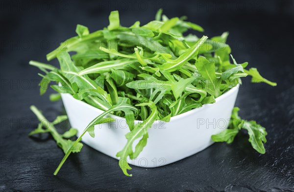 Fresh Arugula (selective focus) as detailed close-up shot on vintage background